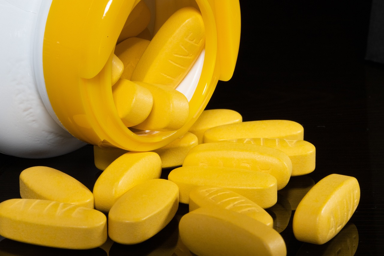 Yellow pills coming out of a pill bottle demonstrating prescription drug possession