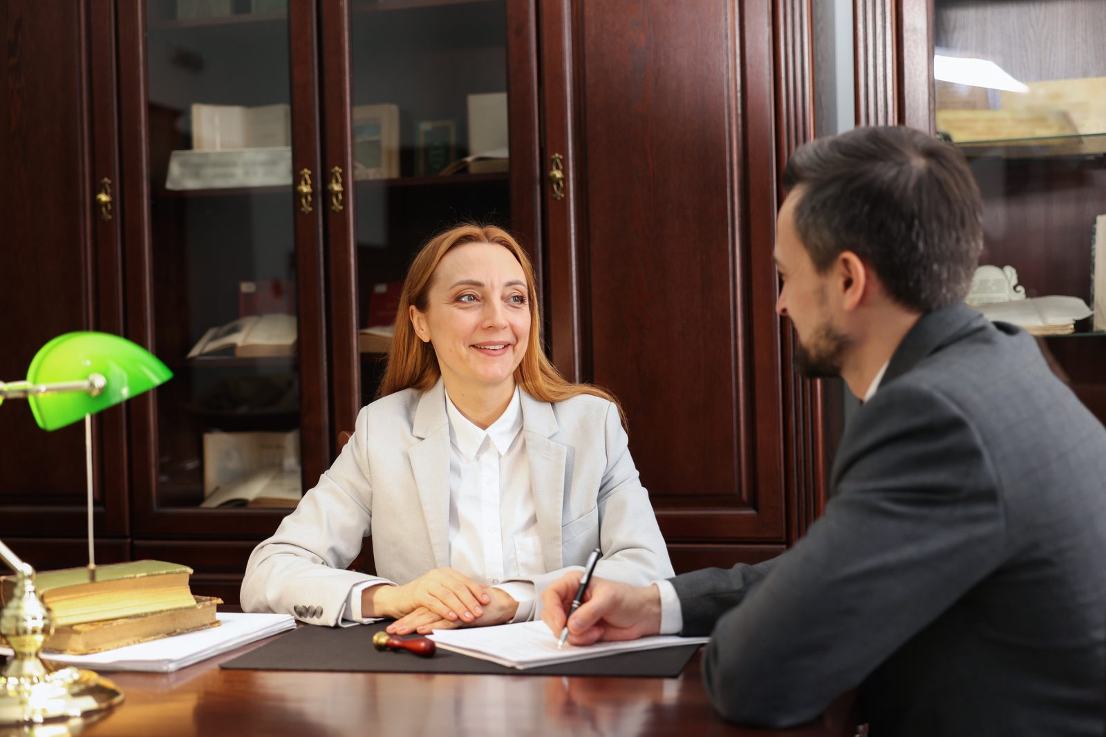 Attorney and client reviewing and signing documents at a desk