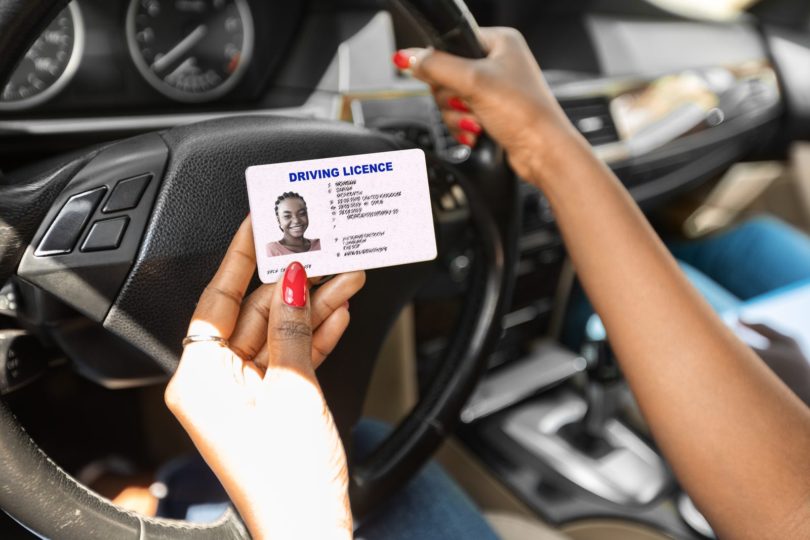 Woman behind the wheel holding up her driving license