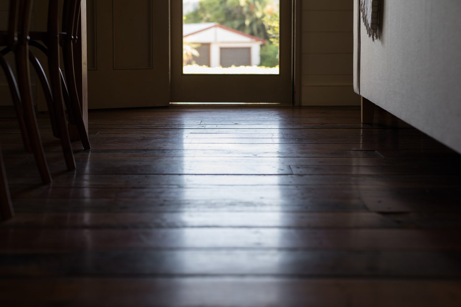 Open home doorway with wooden floor lit by sunlight, representing entry as the defining element of burglary