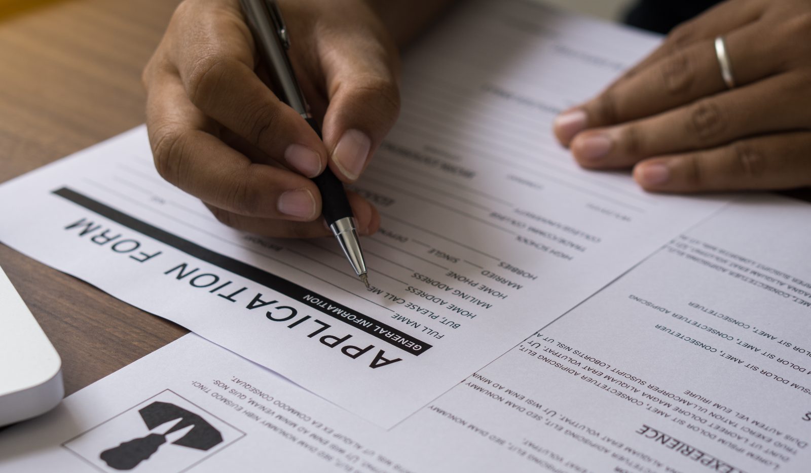 Person filling out an application form with a pen